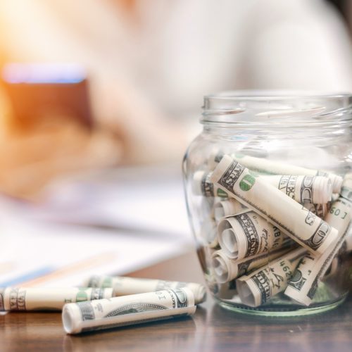 [fpdl.in]_jar-with-rolled-banknotes-table-laptop-papers-woman-background_1268-17480_full